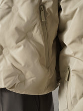 Greigefarbene Steppjacke mit Kapuze und Strickeinsatz von 10days – Detailansicht der Brusttasche mit Reißverschluss