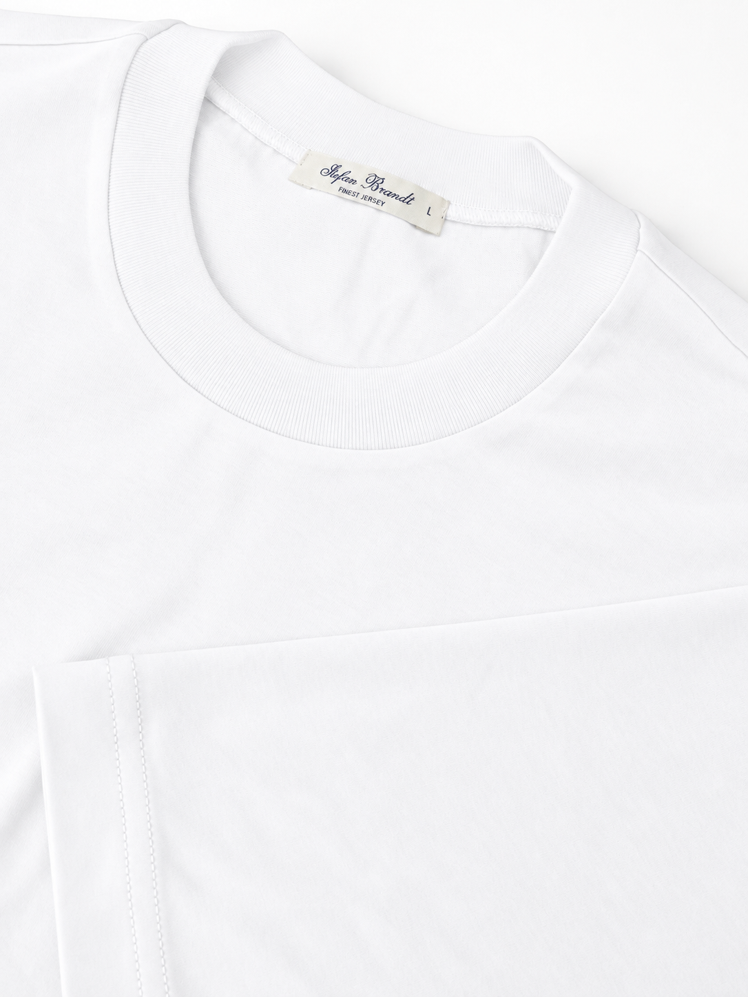 Weißes Jersey T-Shirt von Stefan Brandt – Detailansicht von Kragen und Ärmel mit Label