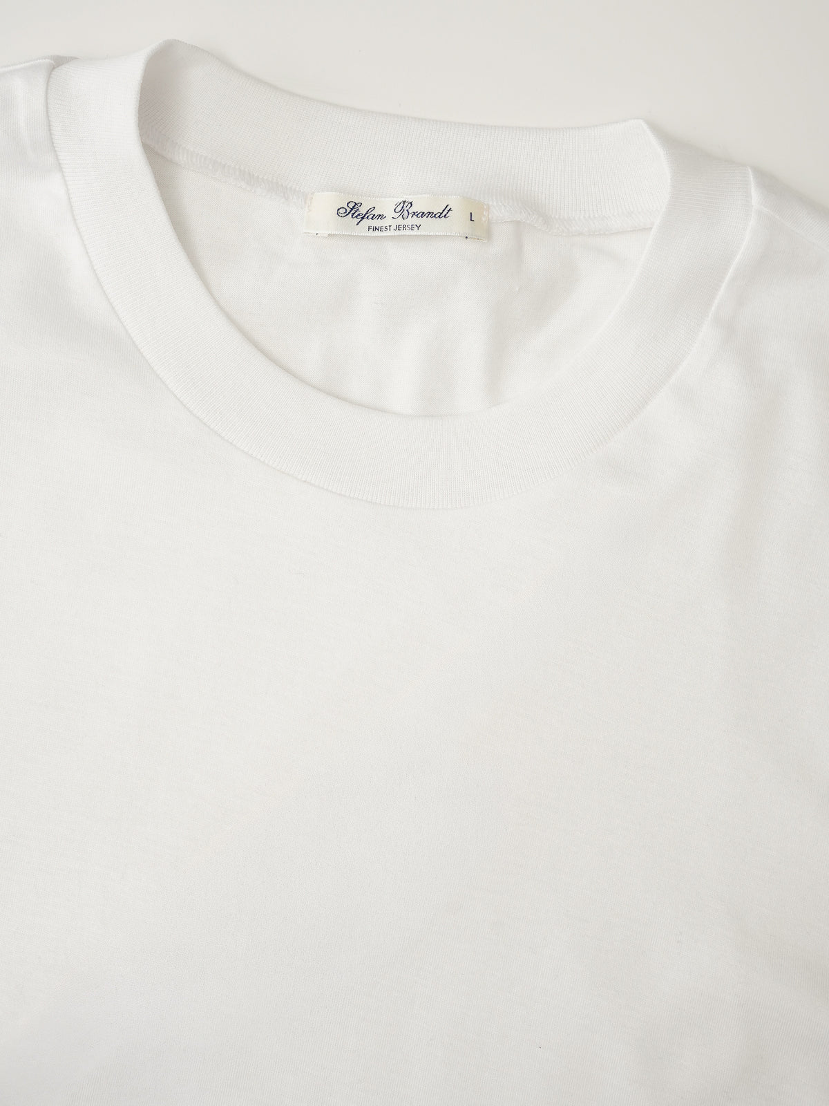 Weißes T-Shirt aus feiner Rippe von Stefan Brandt – Detailansicht des Rundhalsausschnitts mit Label